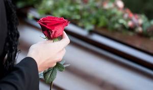 Женщина держит розу у могилы 